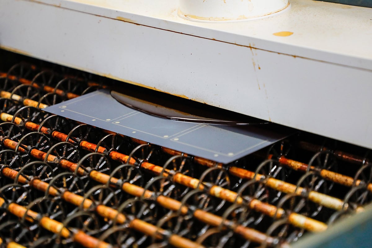 Blue sheet being fed through a large industrial laminating/cutting machine and cover is above it.