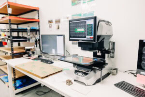 Benchtop scientific imaging system with a large screen, on a white lab bench beside a keyboard and computer monitor in a workspace.