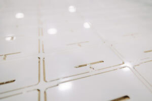 Close-up of white tiled surface with narrow gaps and subtle gold-toned lines, with soft reflections.