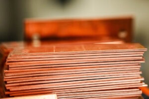 Stack of copper sheets stacked neatly on a workshop bench, edges aligned.
