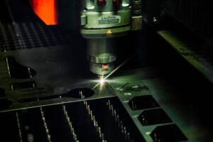 Laser cutting machine in operation cutting metal sheet, sparks flying from the cut line.