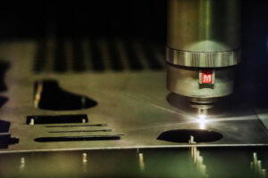 Close-up of a metal control knob with a serrated edge and a red M label on a dark studio device.