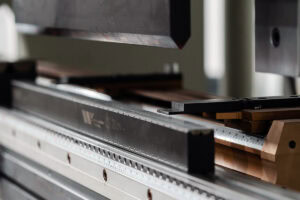 Close-up of a metalworking machine with a ruler scale and movable carriage, showing precision measuring setup.