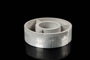 Silver metal ring with an inner hollow bore and cross-braced inner wall on a black reflective surface.