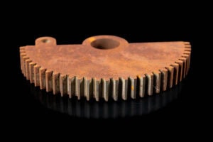 semicircular gear segment with a central bore and evenly spaced teeth along the arc, on a black background.