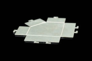 Metal interlocking floor tile piece on a black background, part of a modular mat system