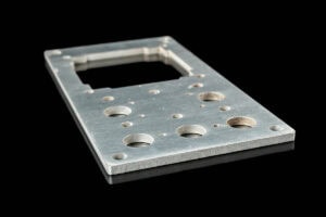 Metal mounting plate with multiple circular holes and a rectangular cutout on a black background, likely for electronics hardware install.