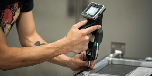 MET_20260518_00224 | MET Manufacturing Group, LLC Close-up of a person using a handheld barcode scanner to scan a label on a metal product on an assembly line
