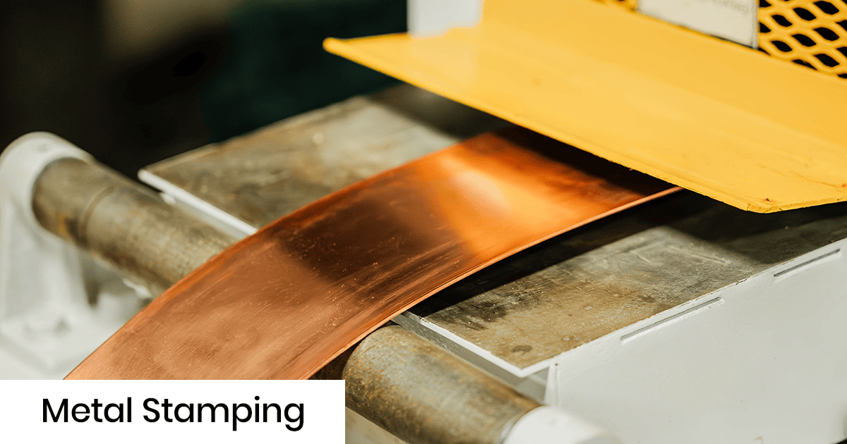 Copper sheet moving through a metal stamping press with a yellow guard in an industrial setting