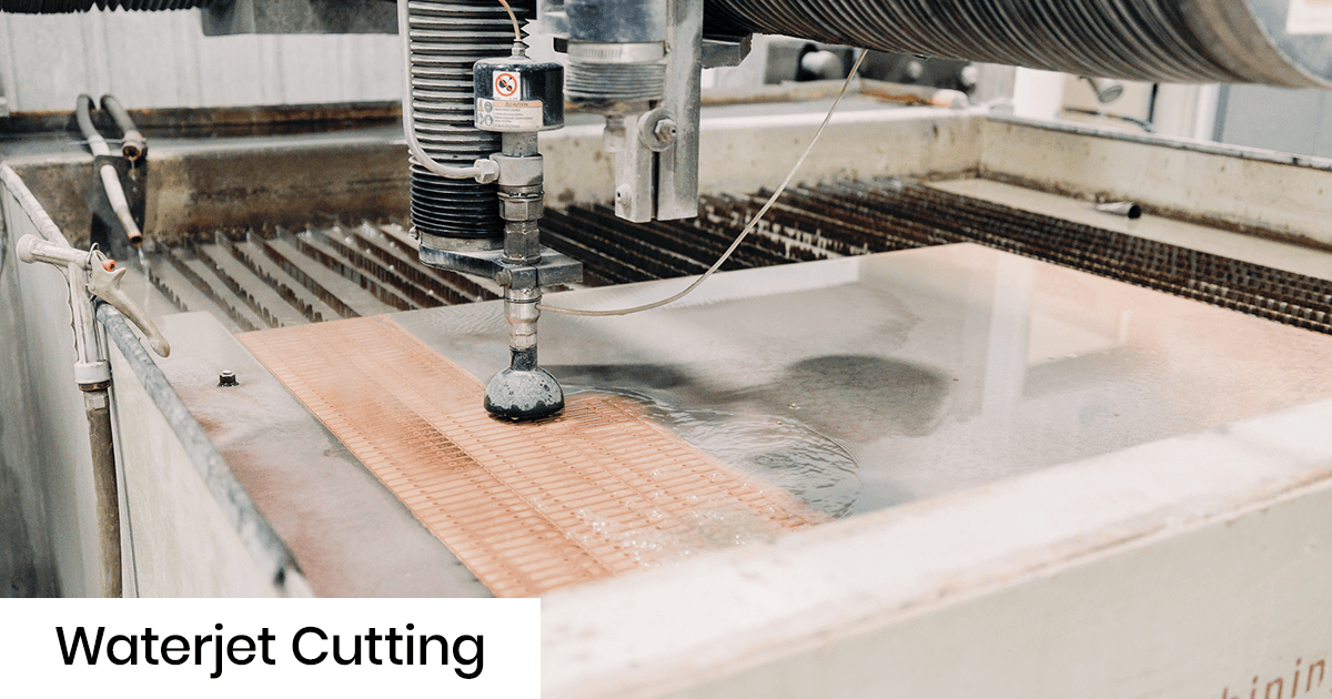 Industrial water jet cutting machine in operation with a nozzle cutting a sheet on a worktable.